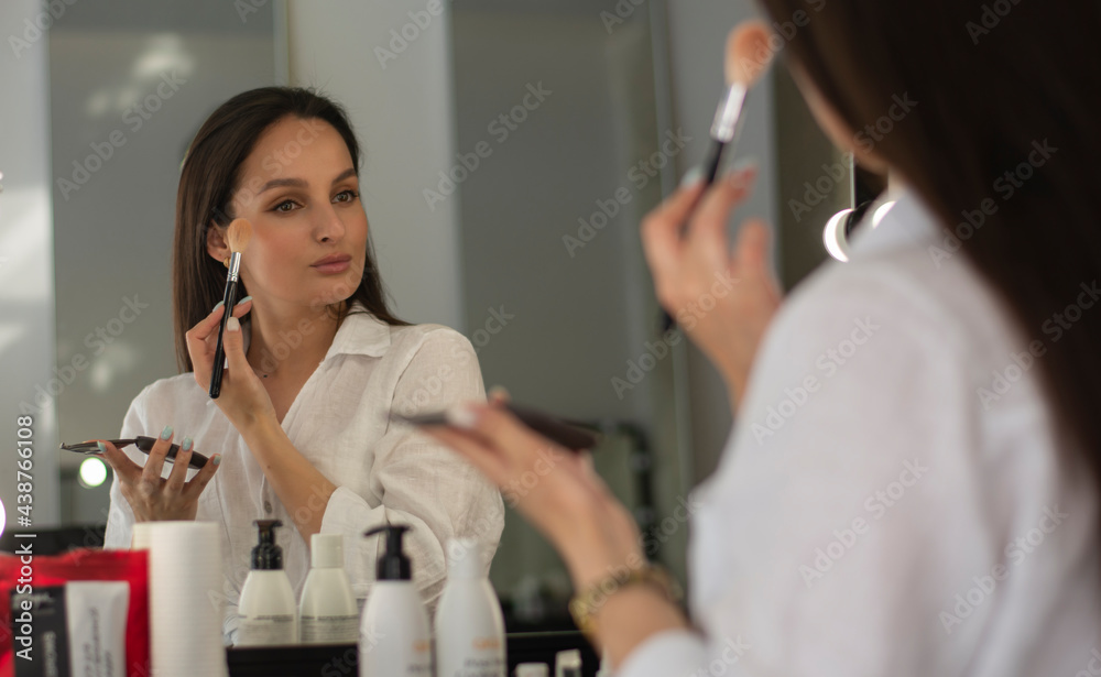The girl is doing her own make-up reflection in the mirror The girl is doing her own make-up reflection in the mirror