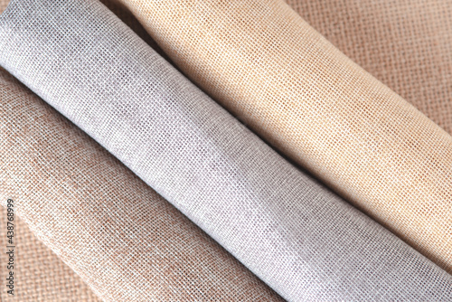 Natural fabrics from organic colors of flax and cotton in rolls, homespun textile handmade. Heap of cloth fabric.