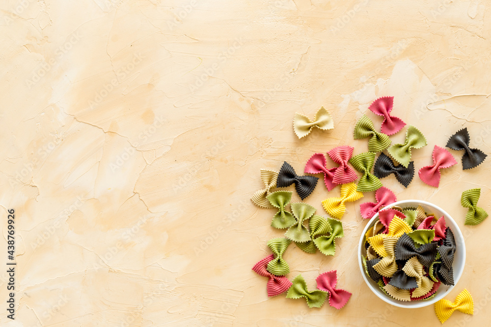 Italian farfalle pasta in bowl. Raw multicolored farfalle pasta, overhead view Italian farfalle pasta in bowl. Raw multicolored farfalle pasta, overhead view
