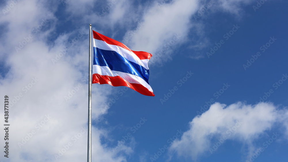 Thailand flag is fluttering in wind. Symbol of Thai nationality waving beautifully against blue sky background with white clouds. Thailand flag is fluttering in wind. Symbol of Thai nationality waving beautifully against blue sky background with white clouds.