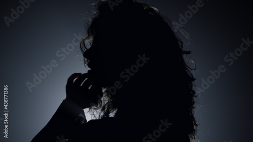 Silhouette pretty woman posing camera in dark. Passionate woman touching hair 