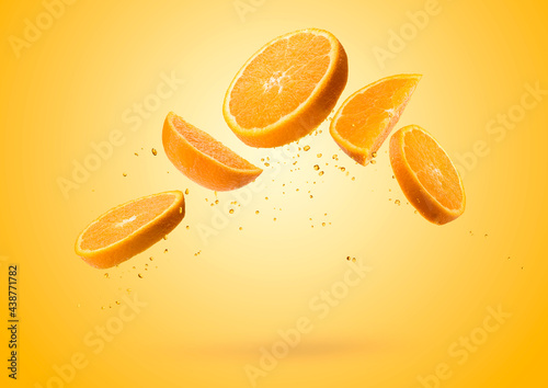 Orange fruit slices flying and dripping on colored background