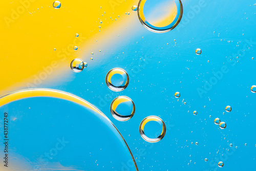 Beautiful macro photo of water droplets in oil with a yellow and blue background. Abstract art