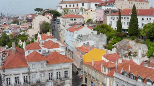 Flying drone camera above narrow street leading uphill to large sacral building, Grace Church and Convent of Our Mother of Grace complex. Lisbon, capital of Portugal.