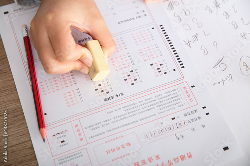 Close-up shot of examinee holding rubber to modify answer sheet
