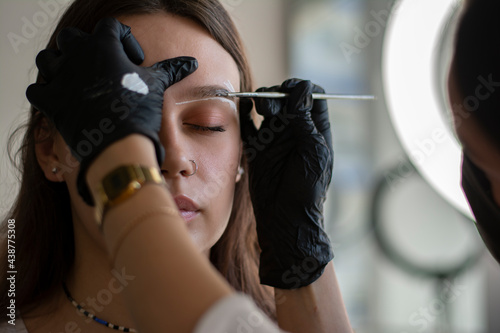 The brow artist prepares the model for the application of eyebrow dye photo