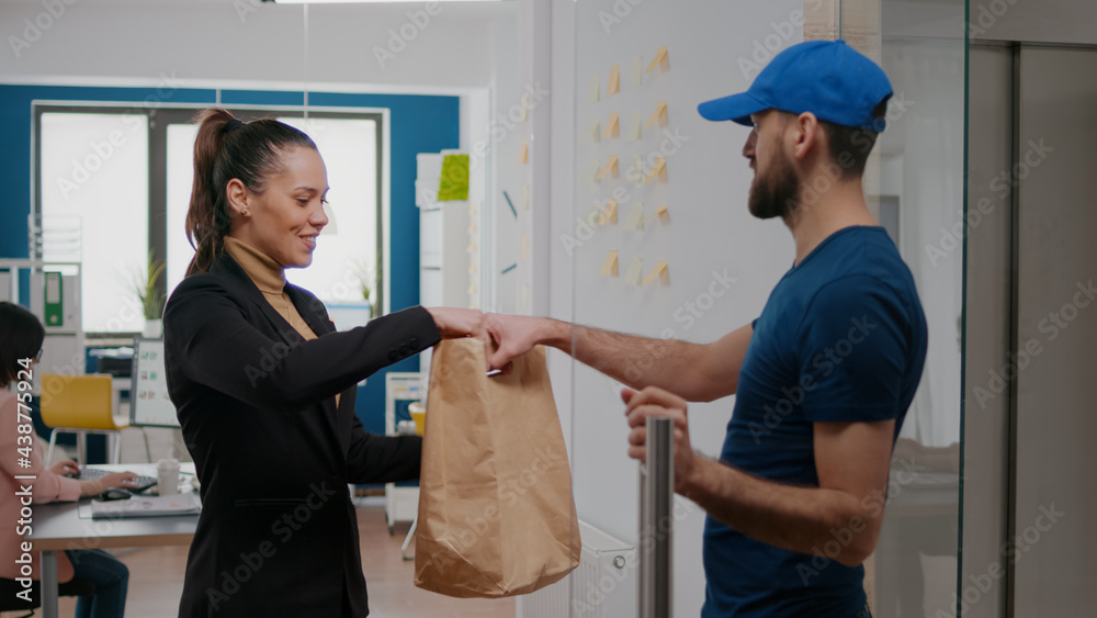 Delivery man giving takeaway package with food order to businesswoman working in startup business company office. Takeout fastfood delivery in corporate job place, lunch meal break paper bag Delivery man giving takeaway package with food order to businesswoman working in startup business company office. Takeout fastfood delivery in corporate job place, lunch meal break paper bag
