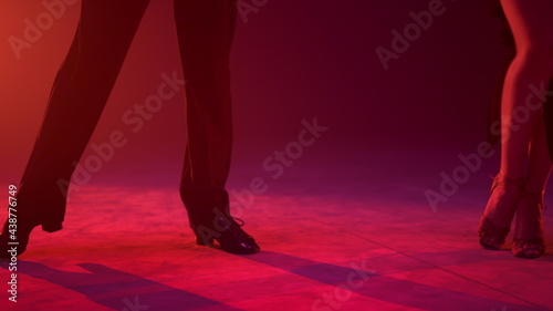 Dancers feet exercising movement on stage. Dance couple performing indoors.
