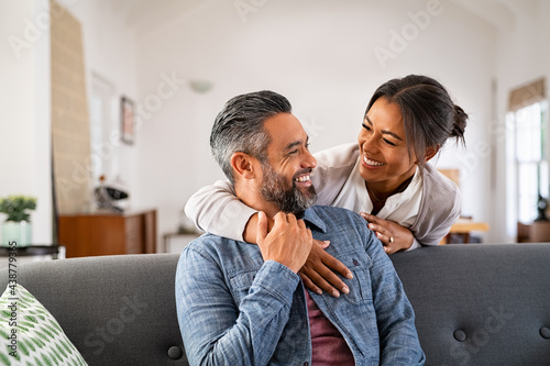 Mature multiethnic couple laughing and embracing at home photo