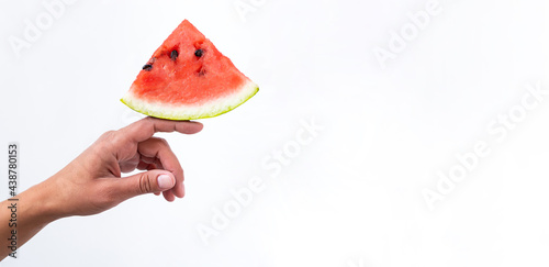 Red watermelon piece in female hand. Creative summer concept. Minimal composition of summer fruit on white background.