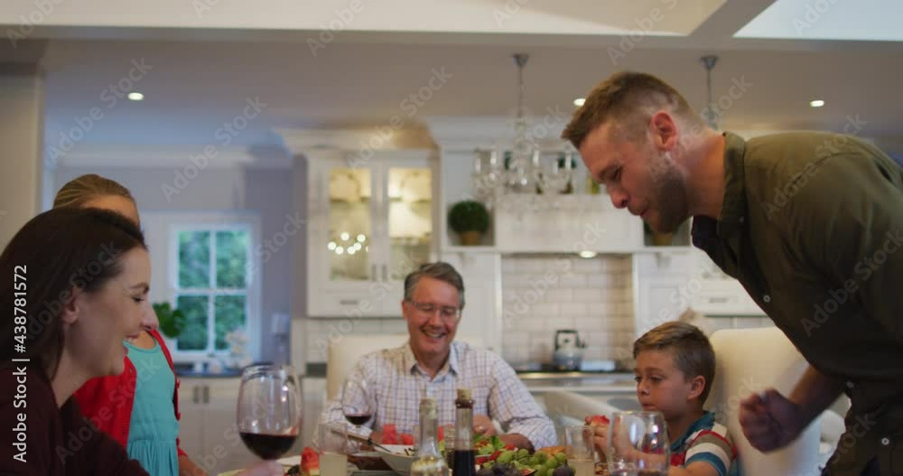 Happy caucasian father giving speech and sitting down at table for family meal Happy caucasian father giving speech and sitting down at table for family meal