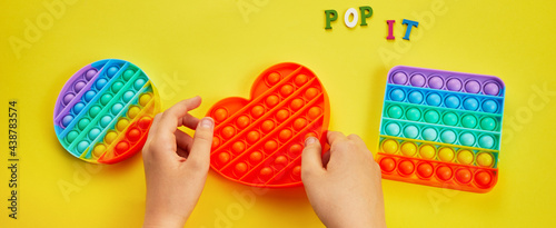 Kid hands playing with colorful pop It fidget toy. Colorful antistress sensory toy fidget push pop it. photo