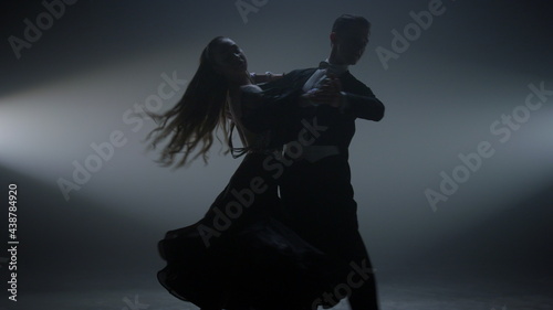 Ballroom pair performing valse on stage. Beautiful couple dancing in dark hall. photo