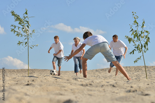 Family playing football on a beach in summer day