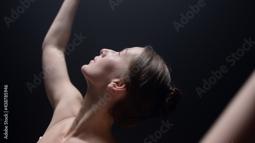 Sensual ballerina dancing indoors. Ballet dancer raising hands in dark class.