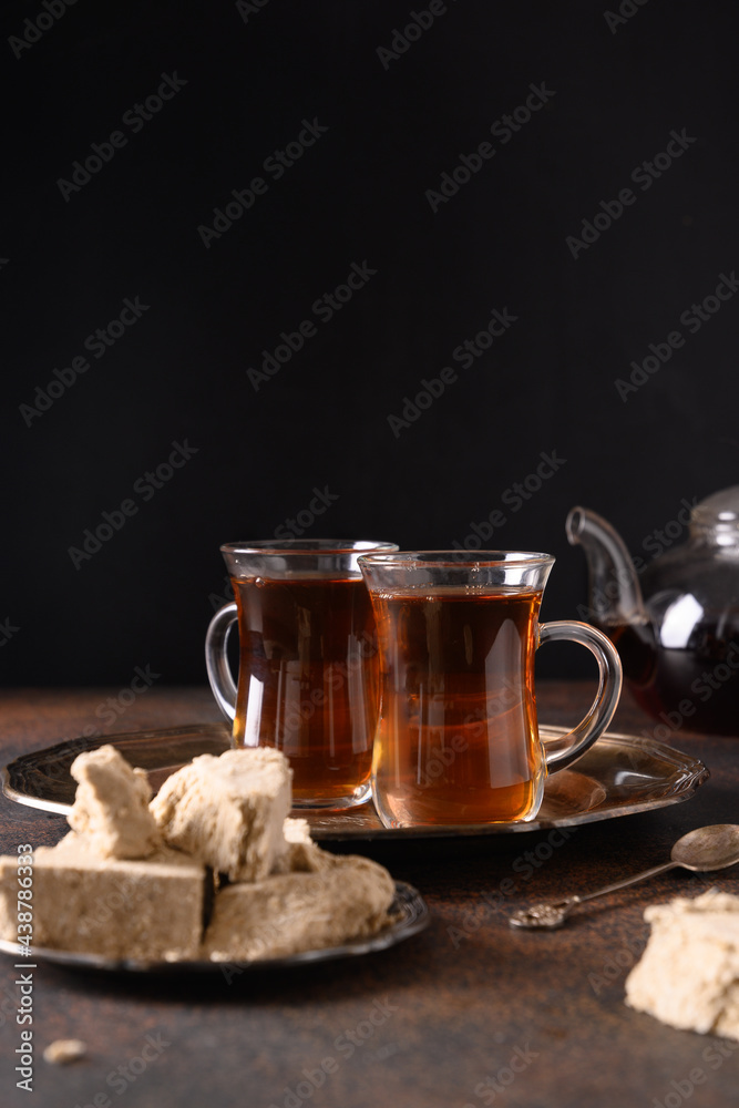 Oriental tea ceremony with sweet halva on a dark brown background. Vertical orientation.