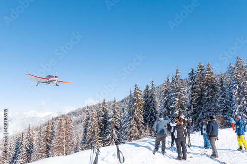 Small propeller aeroplane in mountainous winter landscape with people watching