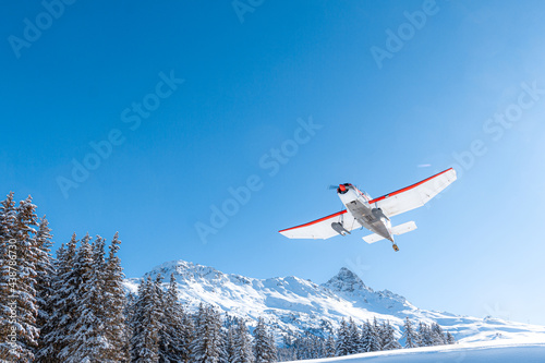 Propeller airplane taking off in mountain winter landscape 