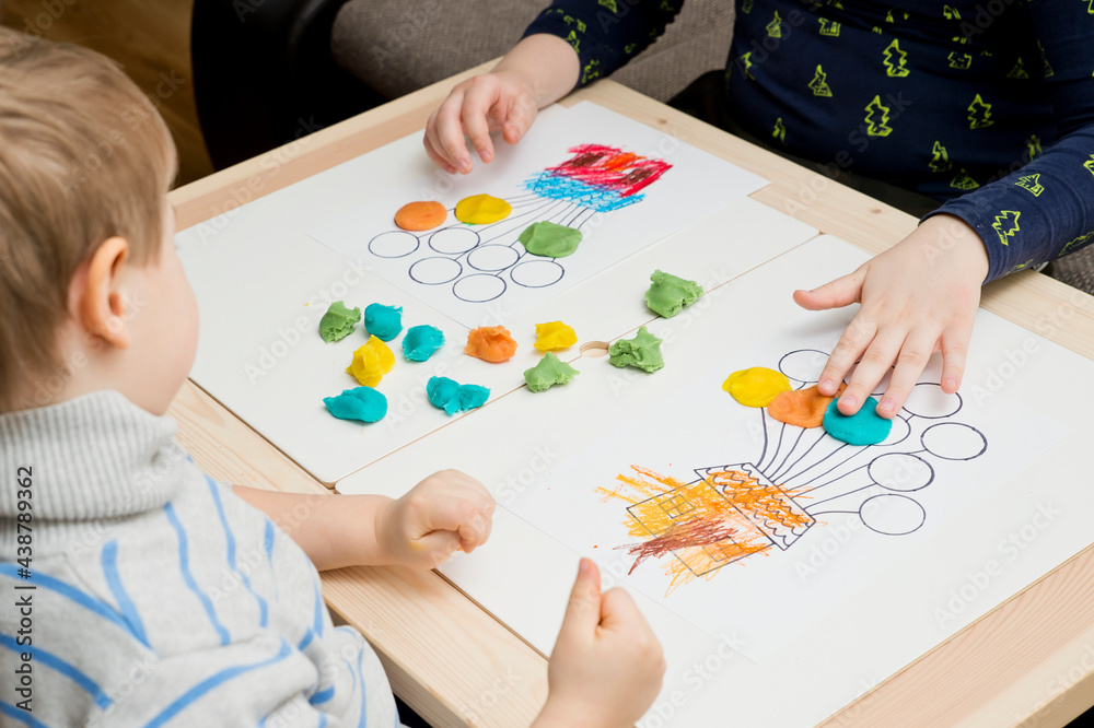 Two pairs of children hands coloring drawing of house with balloons with colored wax crayons. exercise for hand-eye coordination, stimulate imagination, creativity, develop fine motoric skills. Two pairs of children hands coloring drawing of house with balloons with colored wax crayons. exercise for hand-eye coordination, stimulate imagination, creativity, develop fine motoric skills.