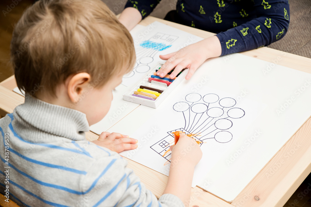 Two pairs of children hands coloring drawing of house with balloons with colored wax crayons. exercise for hand-eye coordination, stimulate imagination, creativity, develop fine motoric skills. Two pairs of children hands coloring drawing of house with balloons with colored wax crayons. exercise for hand-eye coordination, stimulate imagination, creativity, develop fine motoric skills.