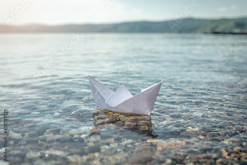 White paper boat in the clear water of Lake Baikal with a stony bottom