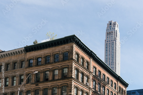 Cityscape of the neighborhood of Tribeca in Manhattan. Old commercial building against skyscraper on blue sky
