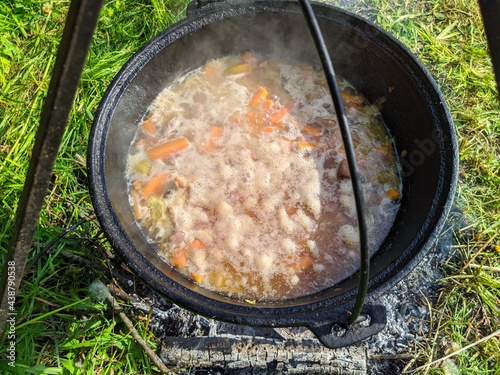 pilaf in a cauldron on an open fire in the daytime in summer.