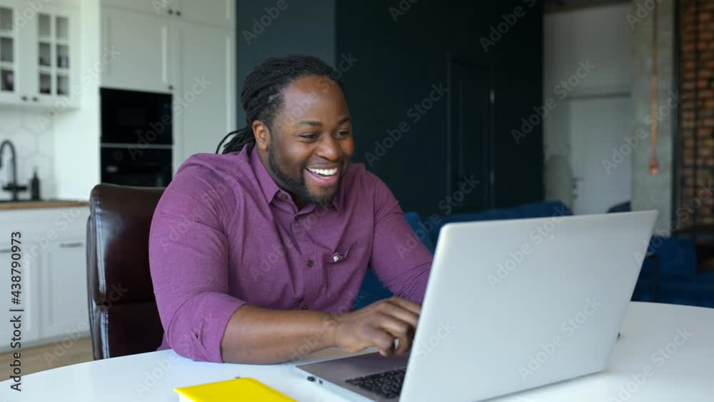 Lucky overjoyed African-American man staring at laptop monitor with happily face expression, screaming yes, received good news or deal, black man celebrating project finished or winning in video game