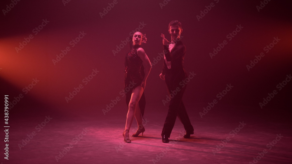 Gorgeous man and woman dancing on illuminated stage. Dance couple performing.
