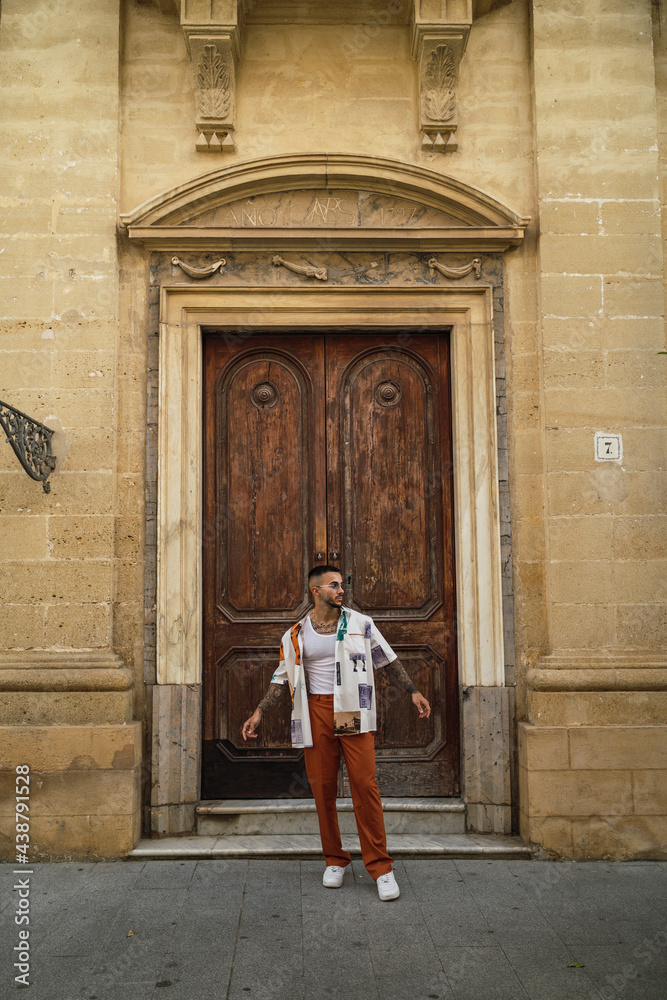 Chico joven guapo tatuado posando en entornos urbanos con ropa a la moda