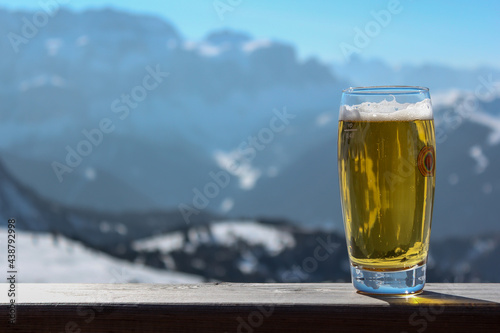 Glass with beer on the background of the alpine mountains of the ski resort