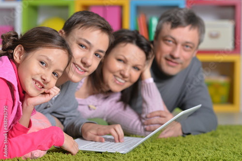 Happy family lying on floor in front of laptop