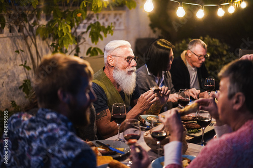 Family people eating at home dinner - Multiracial friends enjoying meal outdoor - Food, friendship, gathering and summer lifestyle concept - Focus on hipster man face