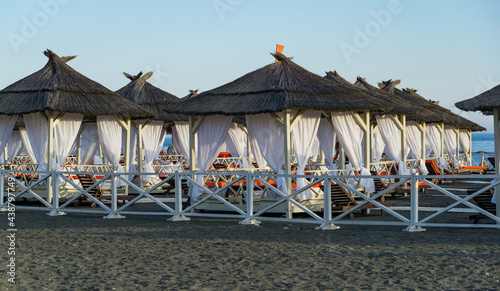 Scenic gazebos with white curtains on Adler pebble beach. Nice and pacific place for rest and relaxation. Black Sea resort Sochi