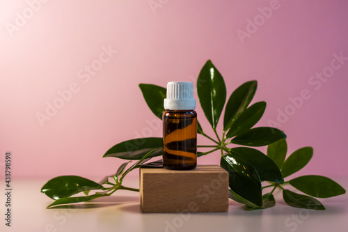 Bottle without label with oil on the stand. Transparent glass container with a dispenser on a beige-pink background. Product banner. Space for text  design.