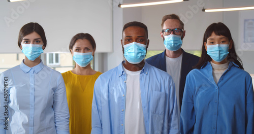 Multicultural businesspeople wearing safety mask standing in office