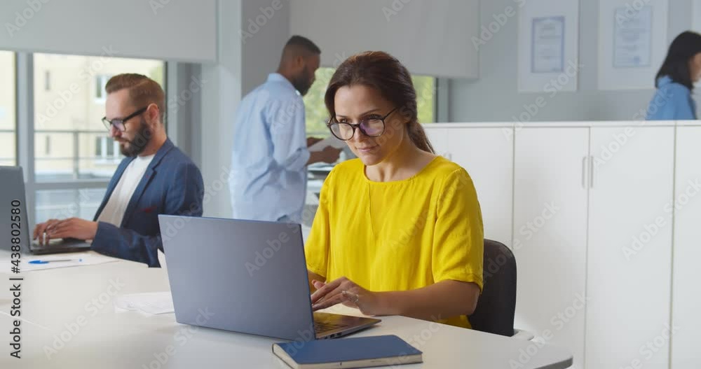 Caucasian woman working in modern office holding documents using computer