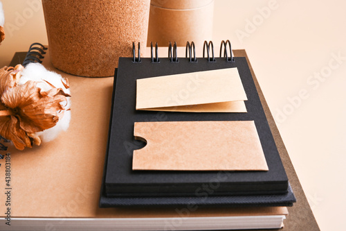 branding mockup with many craft paper and put coffee to go in kraft packaging, eco-friendly stationery and cotton branch. Office desk with a paper notepad and a box of pencils. Mockup.  photo