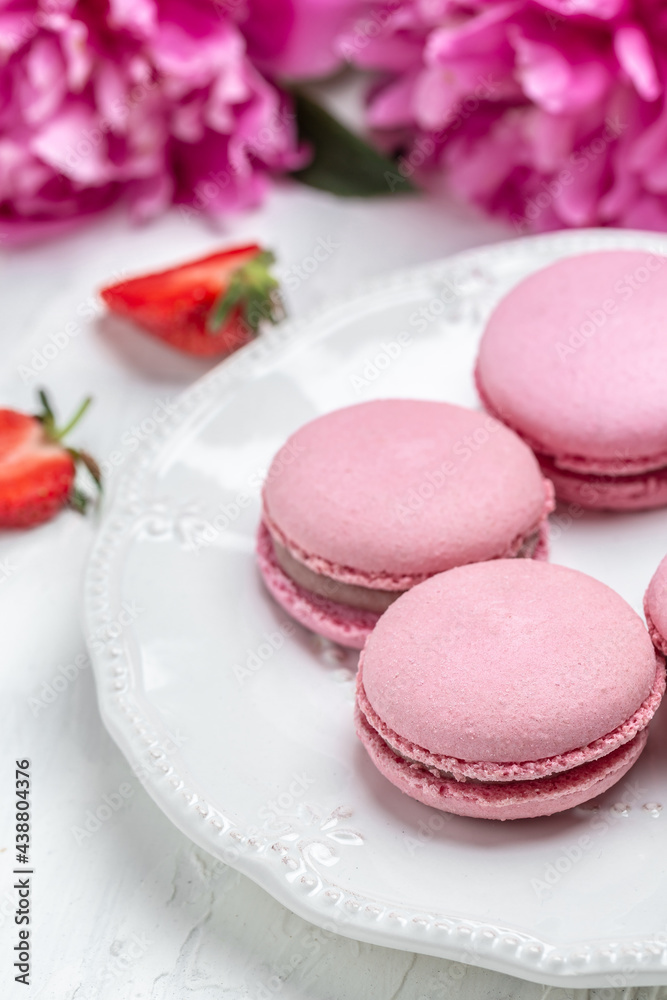 Pink peony with macarons on a white kitchen table, place for text, vertical image. top view Pink peony with macarons on a white kitchen table, place for text, vertical image. top view