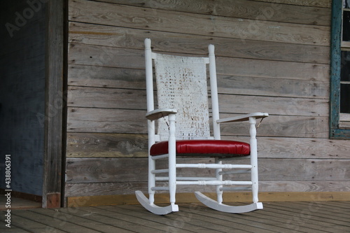 White rocking chair on the porch of an abandoned house.