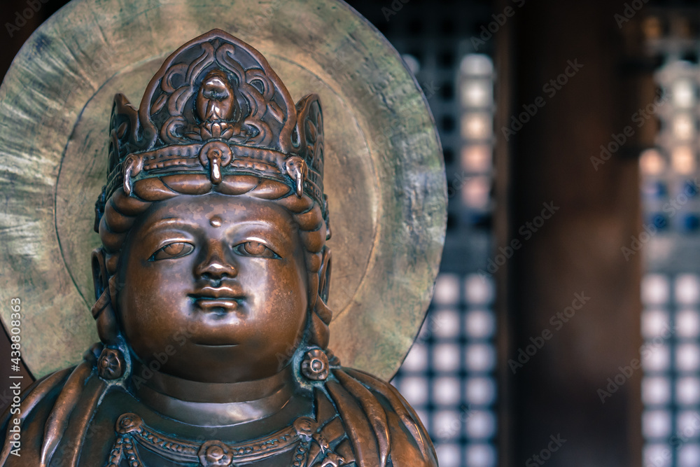 Obraz premium Small bronze Buddha statue with crown on his head in an old Buddhist temple of Kiyomizu Dera in Kyoto, Japan. Arts and symbols of Buddhism in the far east.