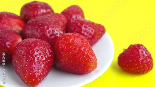 Red strawberry on yellow background close up spinning