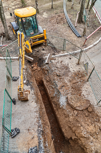 Excavator with bucket stands by deep pit change water pipes