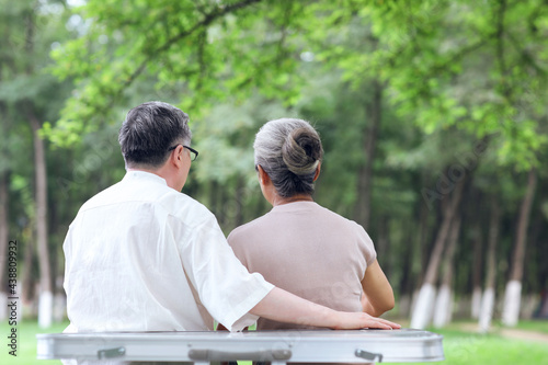 Happy old couple sitting on chairs in outdoor park