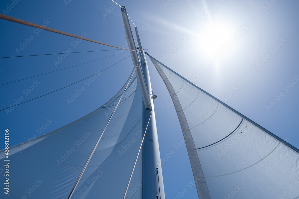 Yacht sails on clear blue sky background. Sailing with the wind at open sea ocean, summer holidays Yacht sails on clear blue sky background. Sailing with the wind at open sea ocean, summer holidays