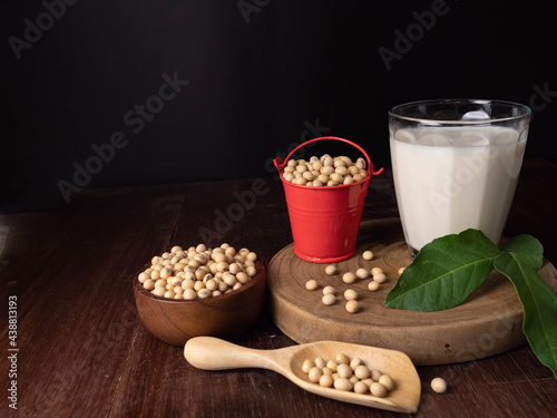 Soybeans in bowl and orange bucket with a glass of soy milk on wooden floor Features high protein and amino acids.