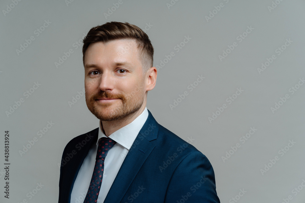 Confident happy executive manager looking at camera and smiling while posing against grey background Confident happy executive manager looking at camera and smiling while posing against grey background