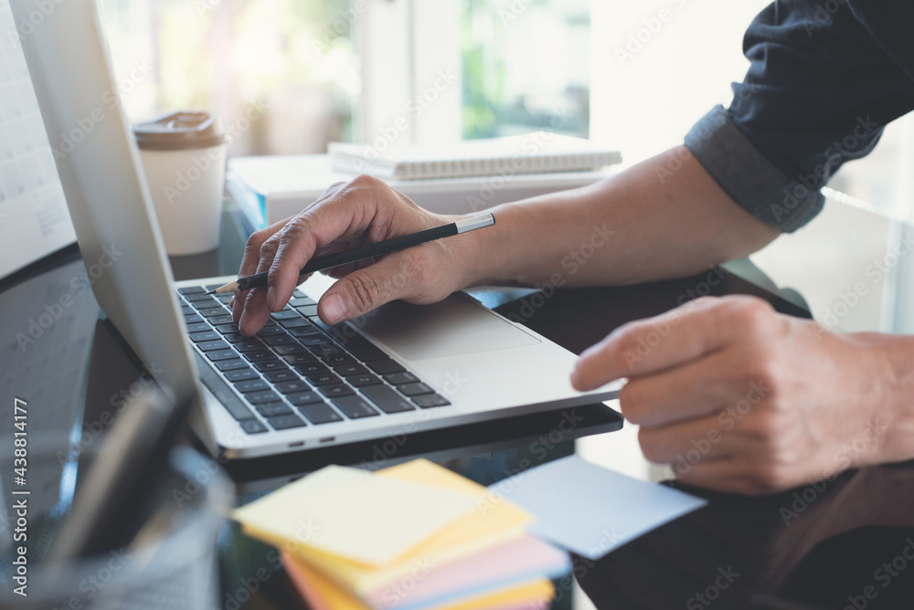 Business man working on laptop computer searching information and planning startup project in office Business man working on laptop computer searching information and planning startup project in office