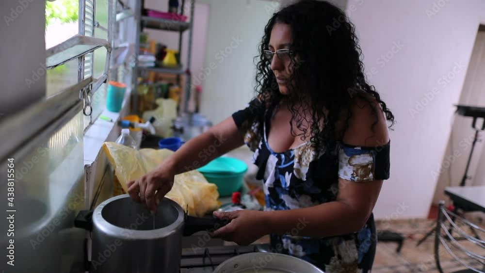 Casual hispanic woman cooking at home, south american lady stirring pot