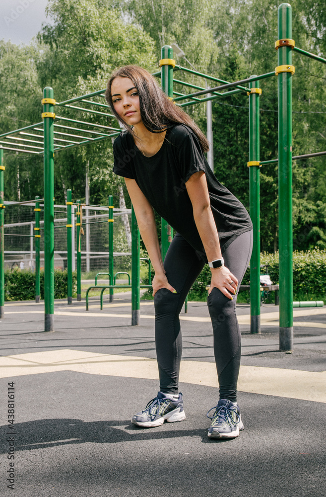 a girl in a black T-shirt and leggings holds her hands on her hips and goes in for sports